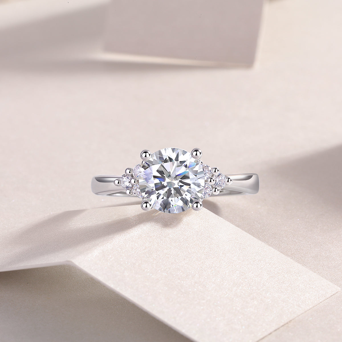 CARISSIE round moissanite solitaire ring, lifestyle shot on textured surface showcasing fire dispersion and elegant silhouette
