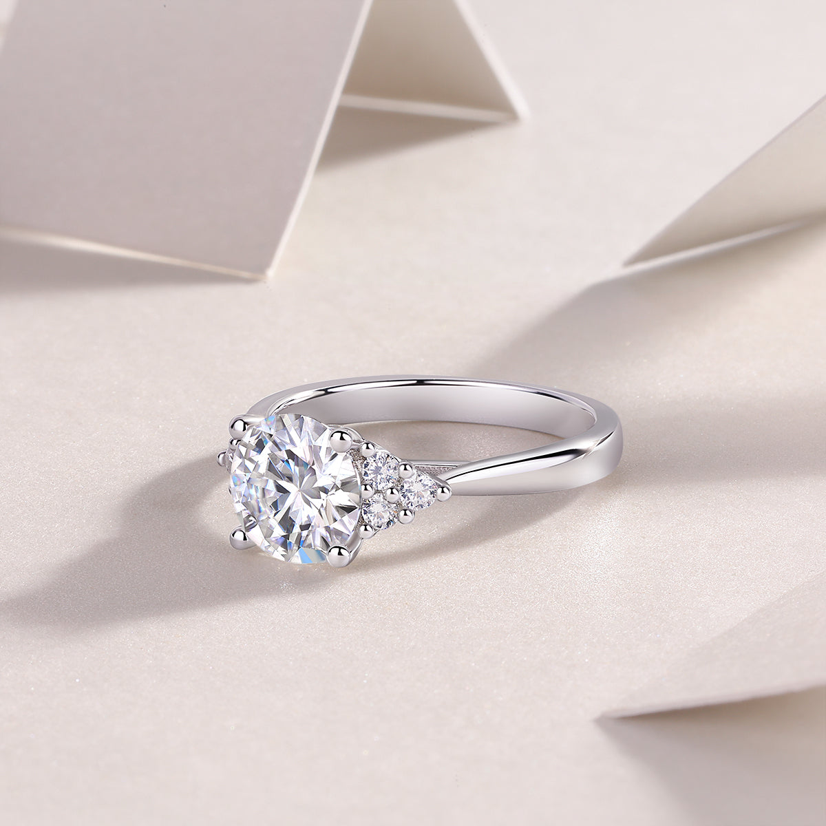 CARISSIE round moissanite solitaire ring, oblique angle emphasizing curved band design and sparkle of clustered side stones