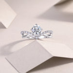 CARISSIE round moissanite solitaire ring, lifestyle shot on textured paper showcasing the sparkling moissanite and silver metal