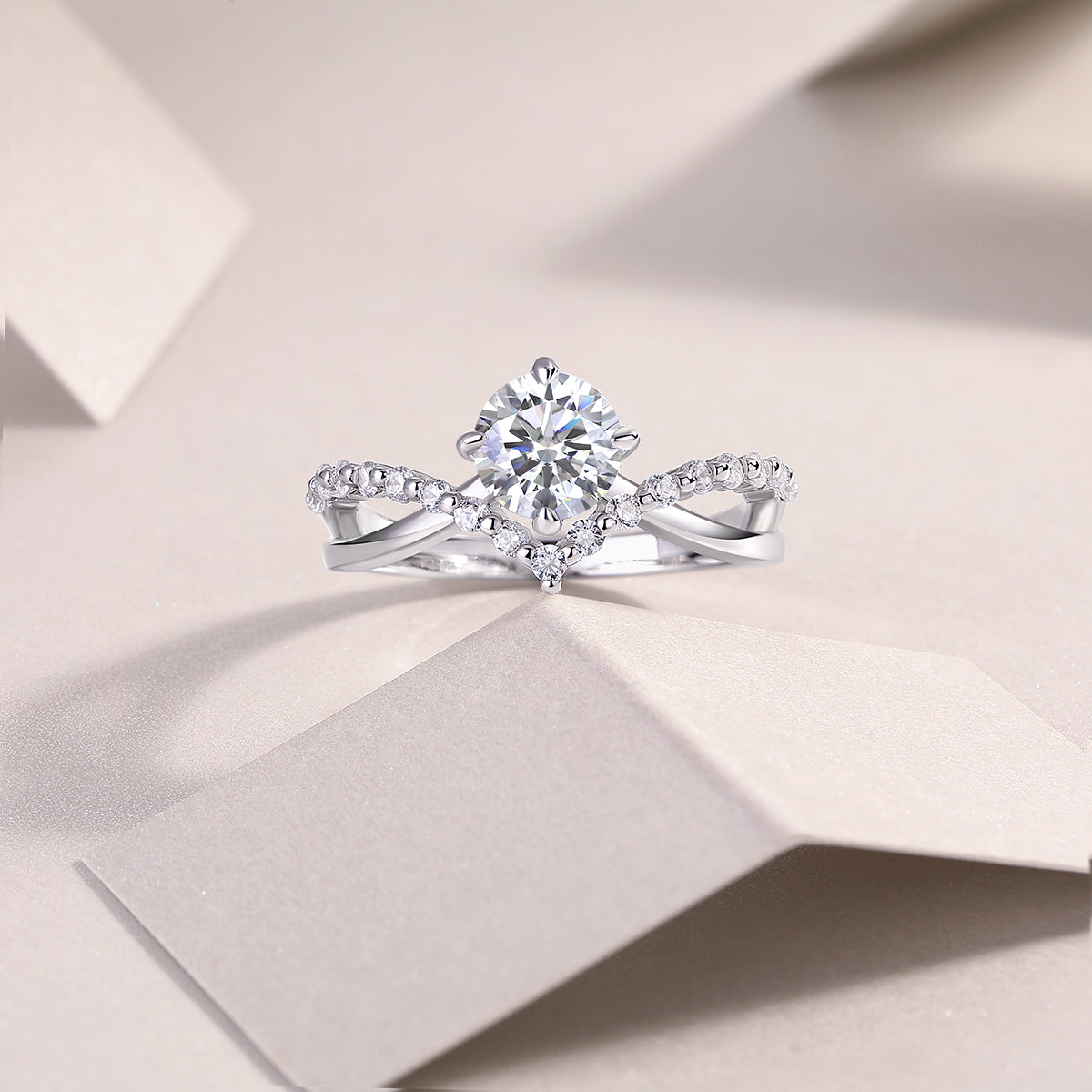 CARISSIE round moissanite solitaire ring, lifestyle shot on textured paper showcasing the sparkling moissanite and silver metal