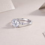 CARISSIE round moissanite solitaire ring, lifestyle shot on textured surface showing interior hallmark and smooth metal finish