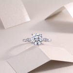CARISSIE round moissanite solitaire ring, overhead view on soft background emphasizing symmetrical design and stone brilliance