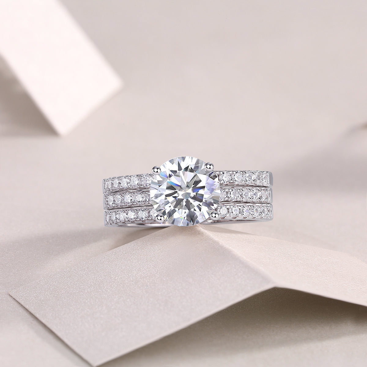 CARISSIE round moissanite solitaire ring set, lifestyle shot on folded paper showcasing the complete stack with a dazzling center stone