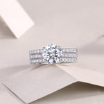 CARISSIE round moissanite solitaire ring set, lifestyle shot on folded paper showcasing the complete stack with a dazzling center stone
