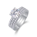 CARISSIE round moissanite solitaire ring set, angled view showing the large center stone and double pavé bands in silver-tone metal