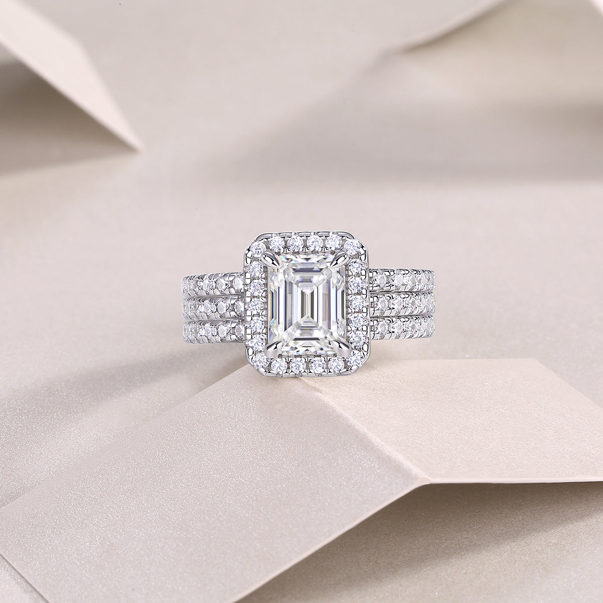 CARISSIE emerald cut moissanite halo ring front view, centered on textured paper to showcase the geometric design