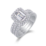 CARISSIE emerald cut moissanite halo ring close-up, diagonal angle revealing prong details and brilliant stone facets