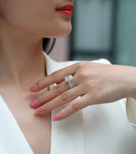 CARISSIE emerald cut moissanite halo ring on hand, displaying the full sparkle of the triple band and center stone