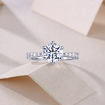 CARISSIE round moissanite solitaire ring, top-down perspective on textured surface displaying full sparkle of center gem