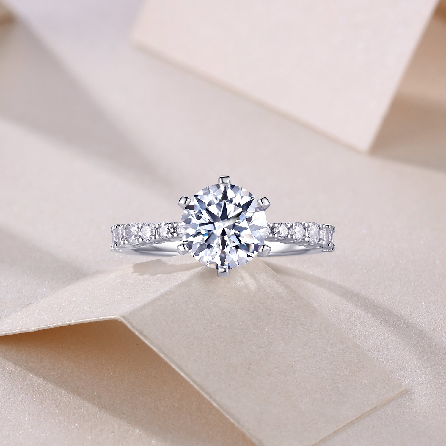 CARISSIE round moissanite solitaire ring, top-down perspective on textured surface displaying full sparkle of center gem