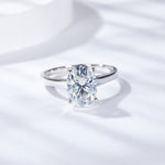 CARISSIE oval moissanite solitaire ring, angled view showing the brilliant stone and polished white gold band on a soft background