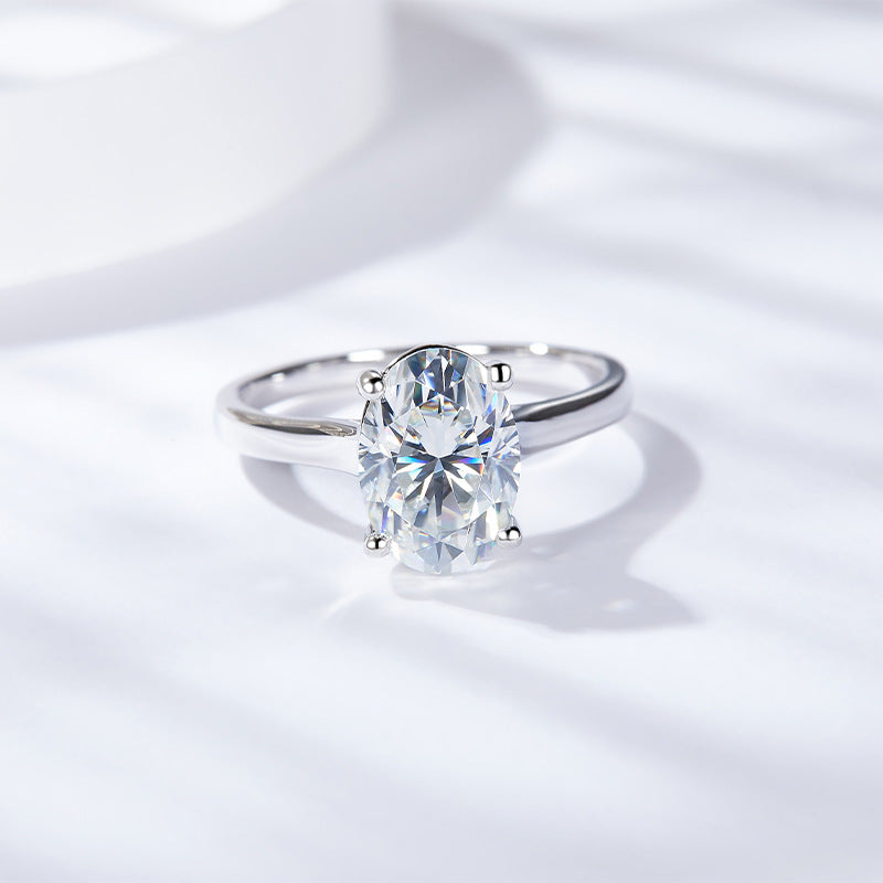 CARISSIE oval moissanite solitaire ring, angled view showing the brilliant stone and polished white gold band on a soft background