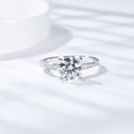 CARISSIE round moissanite solitaire ring, top-down perspective revealing symmetrical prongs and diamond accents in bright light