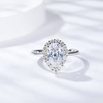 CARISSIE pear moissanite halo ring, top-down view highlighting the brilliant center stone and surrounding diamond halo on a white background