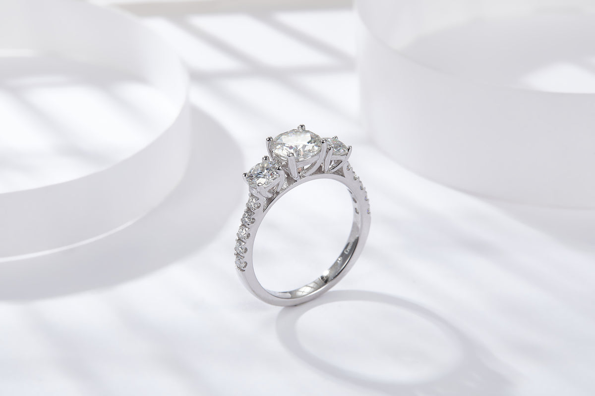 CARISSIE round moissanite solitaire ring, lifestyle shot on white display showing silver-tone metal shine