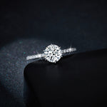 CARISSIE round moissanite solitaire ring, close-up shot focusing on the fire of the main gemstone against a shadowed surface