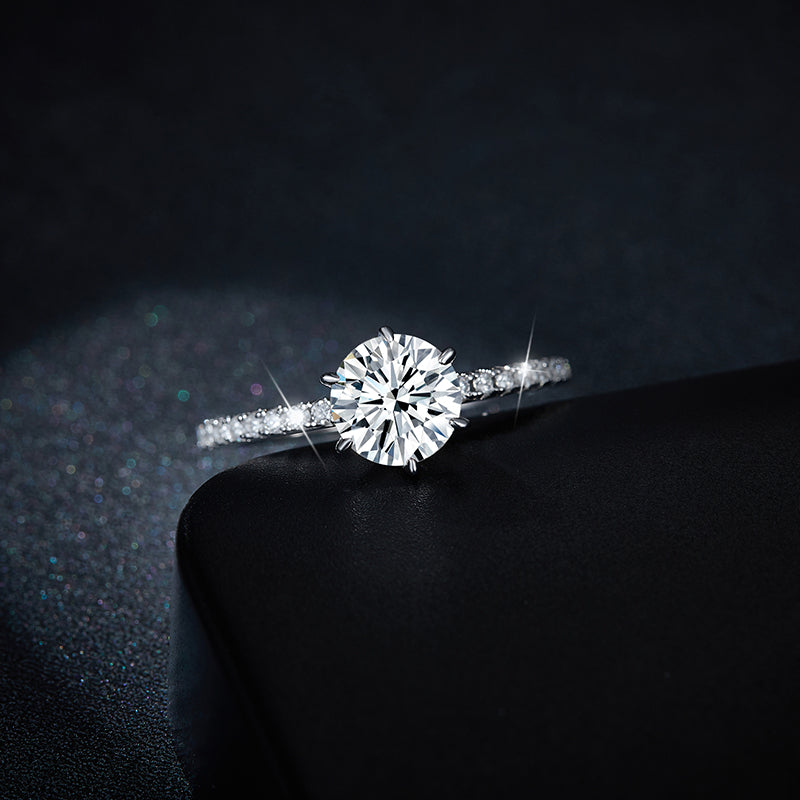 CARISSIE round moissanite solitaire ring, close-up shot focusing on the fire of the main gemstone against a shadowed surface