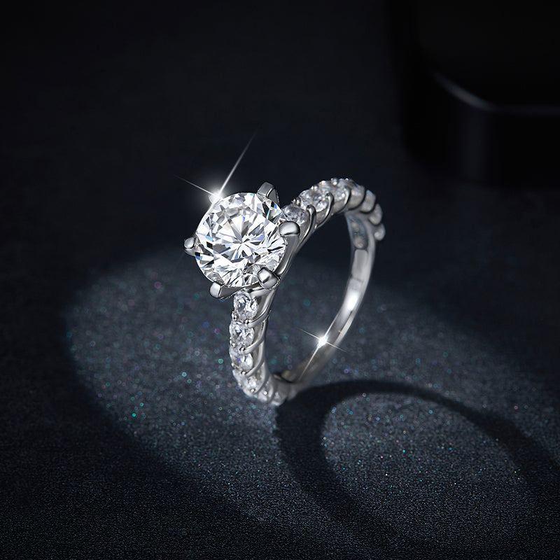 CARISSIE round moissanite solitaire ring, dramatic side profile on dark background emphasizing the prongs and band sparkle