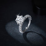CARISSIE round moissanite solitaire ring, dramatic side profile on dark background emphasizing the prongs and band sparkle
