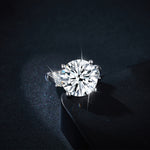 CARISSIE round moissanite solitaire ring, dramatic lighting close-up capturing the brilliance of the main stone against a black surface