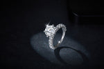 CARISSIE round moissanite solitaire ring, angled lifestyle shot on dark glittery background emphasizing the sparkle of the main gemstone