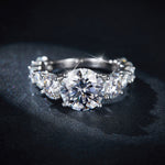 CARISSIE round moissanite solitaire ring, macro view focusing on the brilliant cut facets of the center stone against a textured black surface