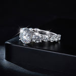 CARISSIE round moissanite solitaire ring, lifestyle image resting on a black box to emphasize the high-profile silhouette and fire