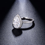 CARISSIE pear moissanite halo ring, side profile view under spotlight revealing the height of the setting and brilliance of the stones