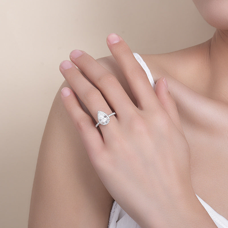 CARISSIE pear shaped moissanite ring, lifestyle shot worn on a woman's hand resting near her shoulder to show scale and elegance