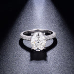 CARISSIE oval moissanite solitaire ring, top-down view under spotlight emphasizing the gemstone's brilliance and silver interior stamp
