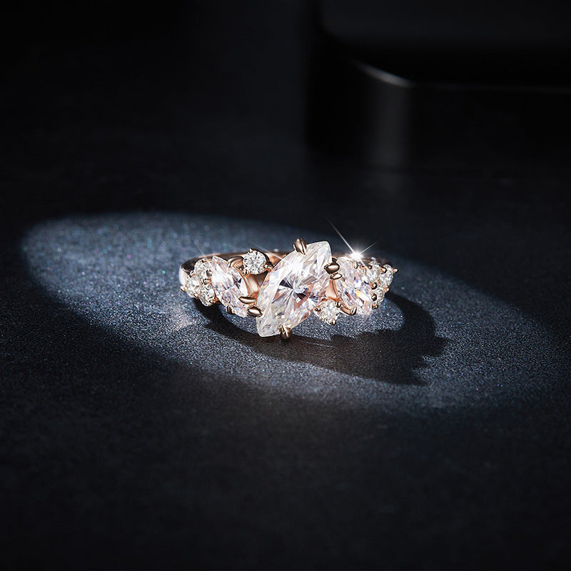 CARISSIE marquise moissanite engagement ring in rose gold, angled view showing floral side clusters on dark textured surface