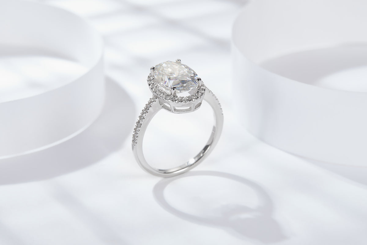 CARISSIE oval moissanite solitaire ring, side profile on white display revealing gallery structure and pavé shoulder stones
