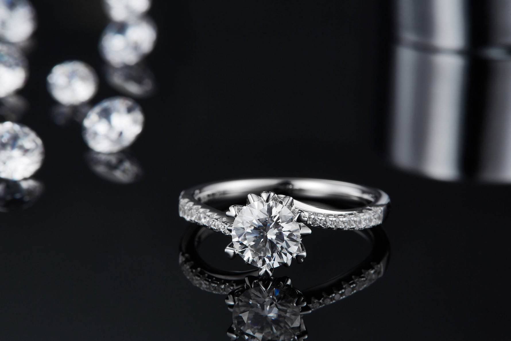 CARISSIE round moissanite solitaire ring, front angle on reflective surface showcasing the mirror-like finish and stone brilliance