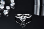 CARISSIE round moissanite solitaire ring, front view on reflective black glass emphasizing stone brilliance