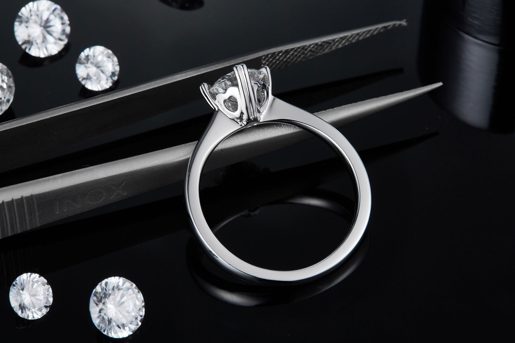 CARISSIE round moissanite solitaire ring, macro shot of setting held by tweezers revealing craftsmanship