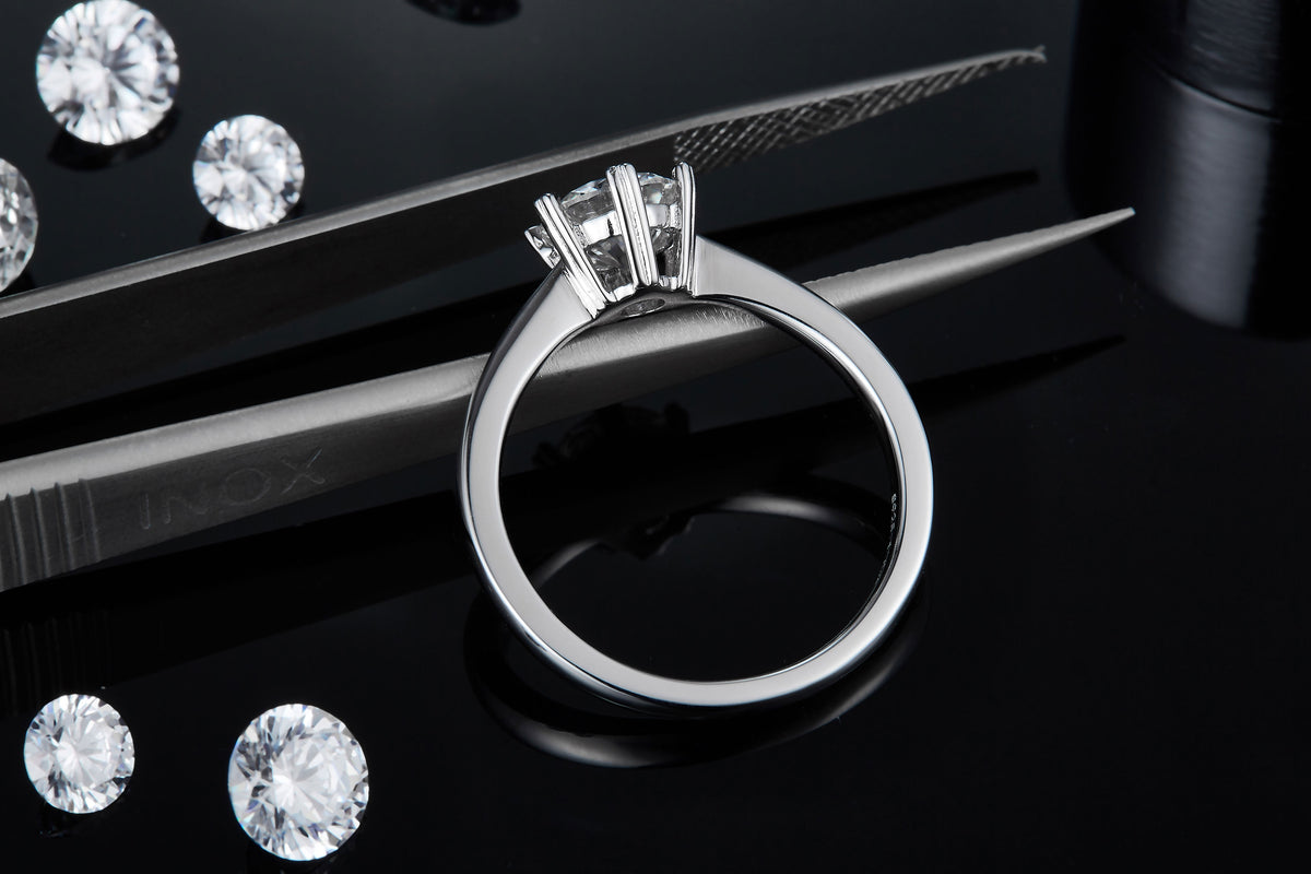 CARISSIE round moissanite solitaire ring, close-up resting on tweezers to showcase the inner band details and craftsmanship