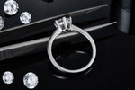 CARISSIE round moissanite solitaire ring, close-up resting on tweezers to showcase the inner band details and craftsmanship