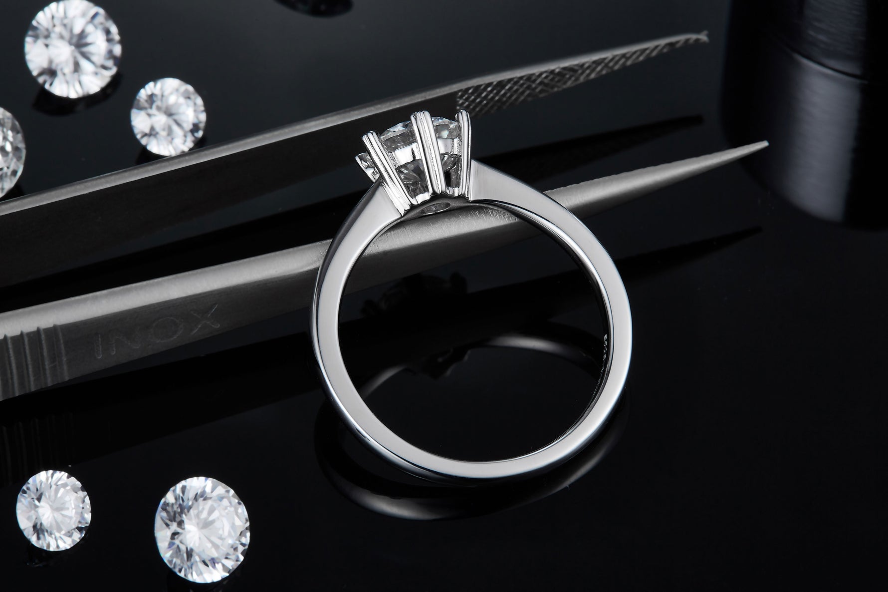 CARISSIE round moissanite solitaire ring, close-up resting on tweezers to showcase the inner band details and craftsmanship