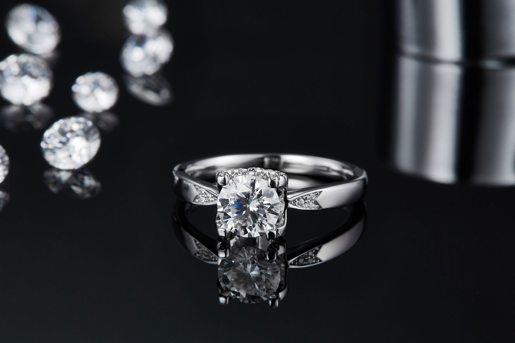 CARISSIE round moissanite solitaire ring, front reflection view on glossy surface showcasing split shank and sparkle