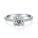 CARISSIE round moissanite solitaire ring, front view highlighting four-prong setting and channel-set accents