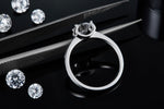 CARISSIE round moissanite solitaire ring, close-up of the prongs holding the gemstone against a dark backdrop