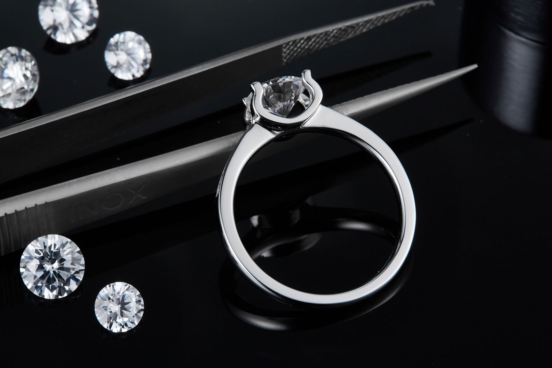 CARISSIE round moissanite solitaire ring, close-up of the prongs holding the gemstone against a dark backdrop