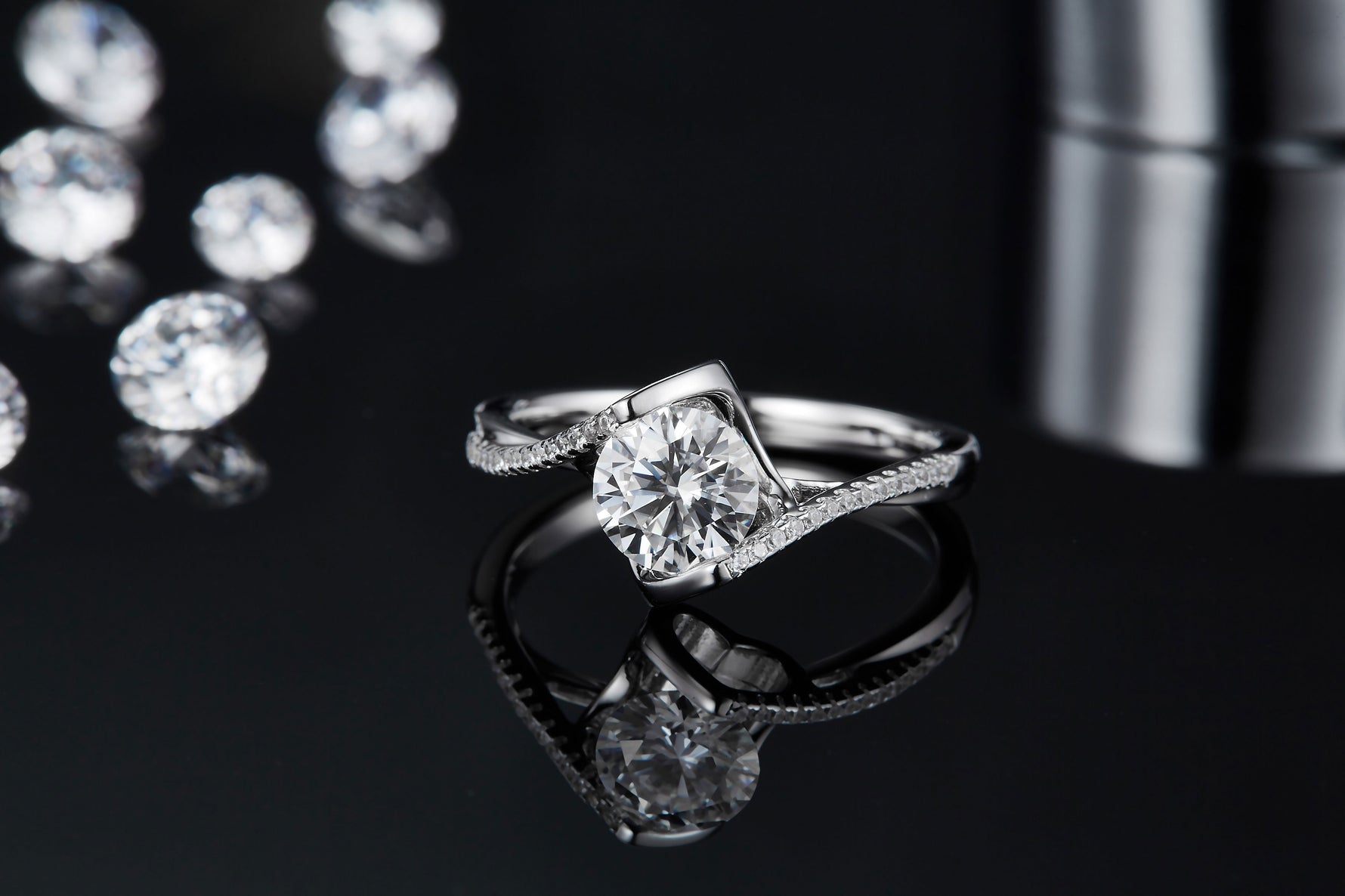 CARISSIE round moissanite bezel ring, close-up front view emphasizing the sparkle of the main gem against a black backdrop.