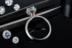 CARISSIE round moissanite halo ring, held by tweezers to show the inner band details, heart gallery, and two-tone metal finish.