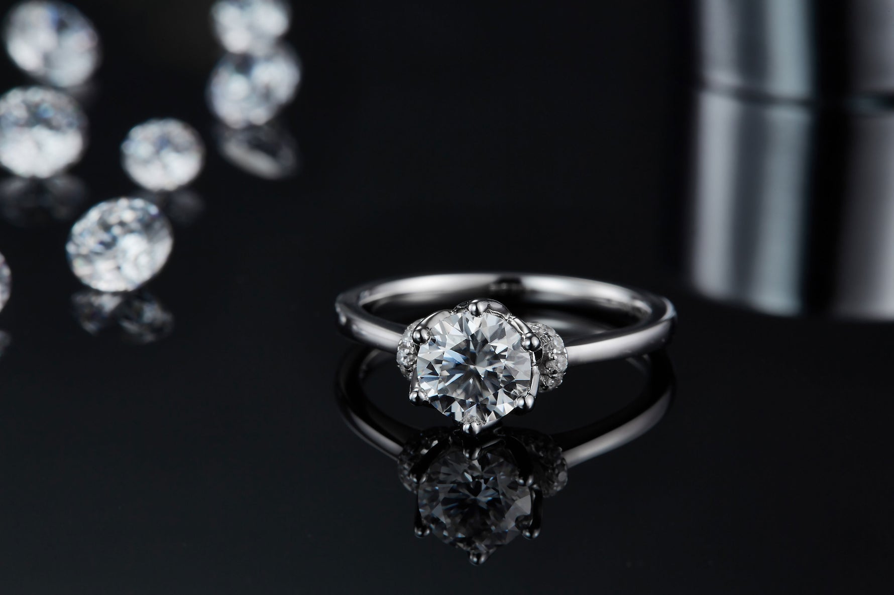 CARISSIE round moissanite solitaire ring, low angle perspective on reflective surface emphasizing brilliance and clarity