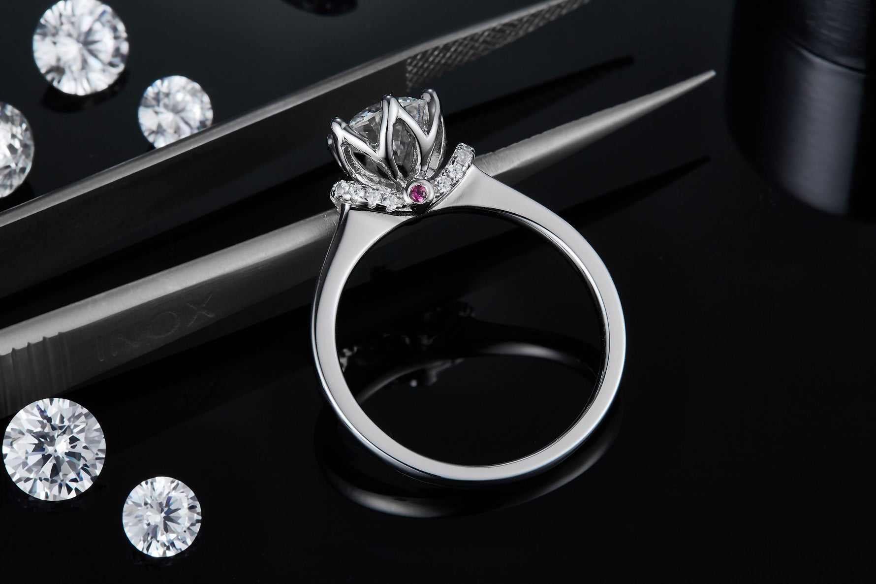 CARISSIE round moissanite solitaire ring, detailed macro shot resting on tweezers to show craftsmanship