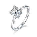CARISSIE round moissanite solitaire ring, angled view highlighting the geometric H-shaped prongs and pavé accents on a white background