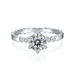 CARISSIE round moissanite solitaire ring, front view showcasing the six-prong setting and interlocking metal texture