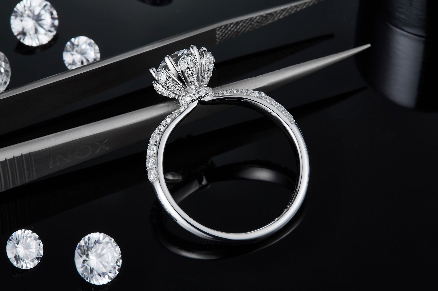 CARISSIE round moissanite solitaire ring, side profile resting on tweezers to show detailed metalwork