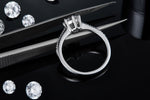 CARISSIE round moissanite solitaire ring, close-up held by tweezers revealing the interior structure of the prongs